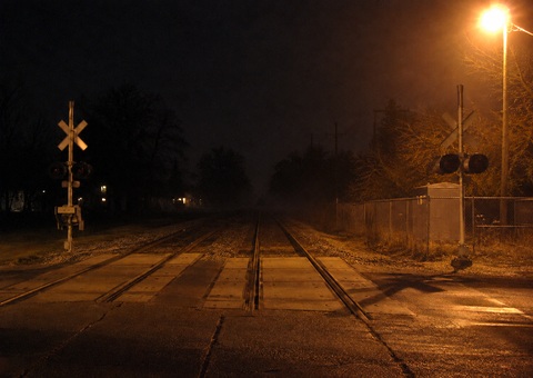 Washington Street NCS crossing Grayslake at night, tracks running north toward curve, grade crossing signals visible, sodium vapor light